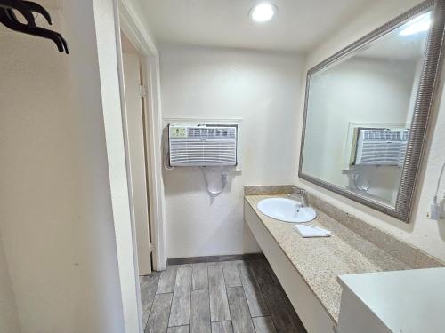 ein Bad mit einem Waschbecken und einem Spiegel in der Unterkunft Peach City Inn - Marysville/Yuba City in Marysville