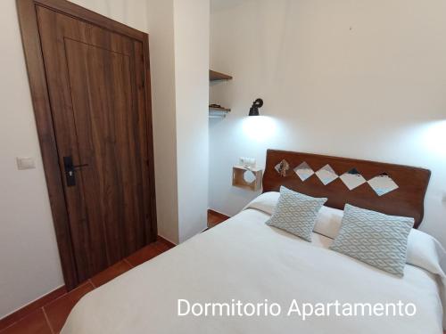 um quarto com uma cama e uma porta de madeira em El Detalle em Zahara de la Sierra