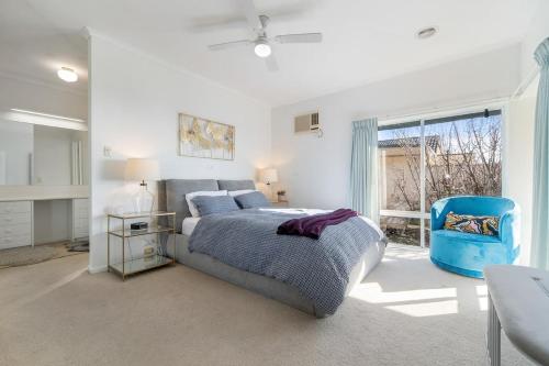 a bedroom with a bed and a blue chair at Dromana Premium Retreat - Stunning views in Dromana
