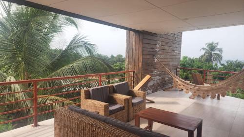 a porch with two chairs and a hammock on a balcony at Appartement Jully/Plage in Kribi