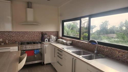 a kitchen with a sink and a large window at Appartement Jully/Plage in Kribi