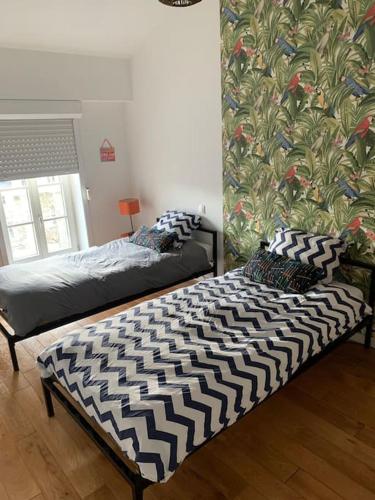 a bedroom with two beds and a wall with a mural at Appartement DuplexCœur de Ville in Metz