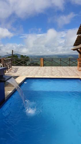 uma grande piscina azul com uma fonte de água em Belaninha em Guaramiranga