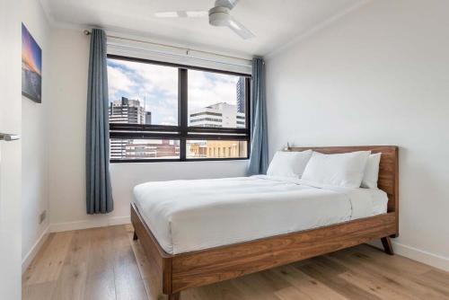 a bedroom with a bed and a large window at Stylish Central City Retreat with Pool & Parking in Brisbane