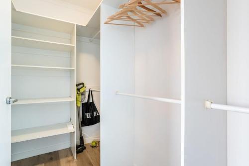 two views of a closet with white shelves at Stylish Central City Retreat with Pool & Parking in Brisbane
