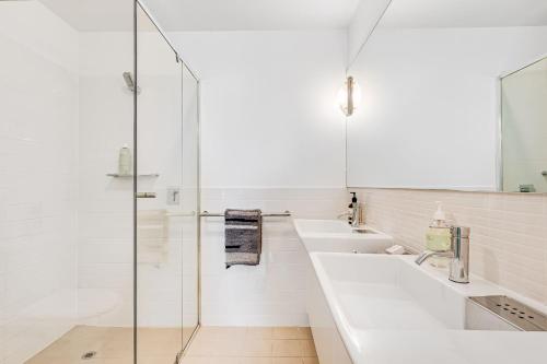 Baño blanco con 2 lavabos y ducha acristalada en Luxury Breeze Beachfront Apartment, en Victor Harbor