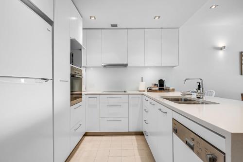 a white kitchen with white cabinets and a sink at Luxury Breeze Beachfront Apartment in Victor Harbor