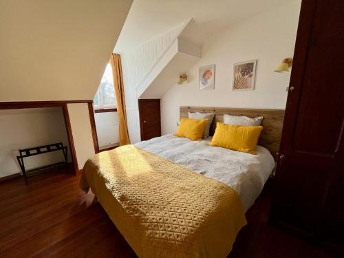 ein Schlafzimmer mit einem Bett mit gelben Kissen in der Unterkunft La Villa Mirabelle 2min d'Arromanches-les-Bains in Tracy-sur-Mer