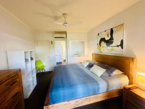 Appartment in Palm Cove في بالم كوف: غرفة نوم بسرير ازرق مع كرسي اخضر