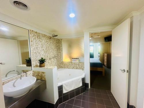 W łazience znajduje się wanna, umywalka i lustro. w obiekcie Appartment in Palm Cove w mieście Palm Cove