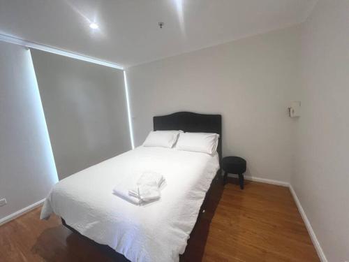 a bedroom with a white bed with a black headboard at Home away from home! in Dubbo
