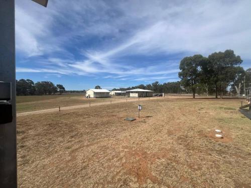 a field with a white barn in the distance at Home away from home! in Dubbo