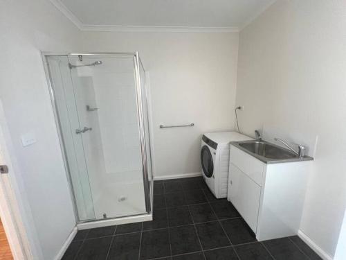 a bathroom with a shower and a sink and a washing machine at Home away from home! in Dubbo