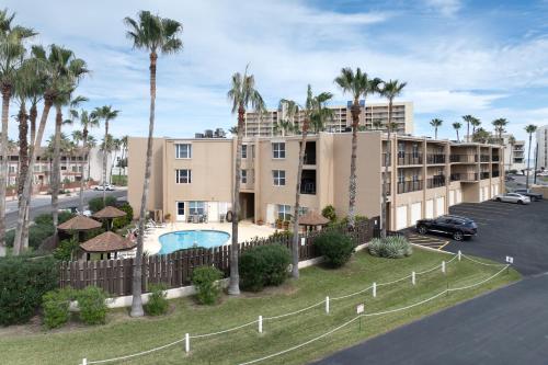 an apartment building with a pool and palm trees at La Casita at Surfside 103 in South Padre Island