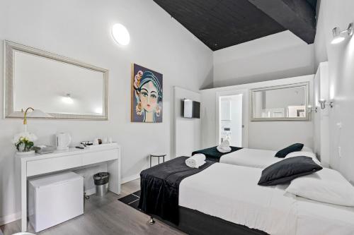 a white bedroom with a bed and a desk at Airport Hotel Sydney in Sydney