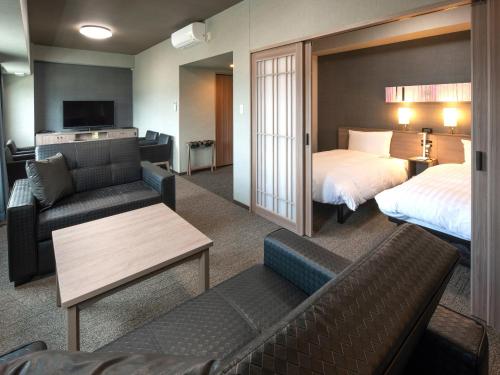 une chambre d'hôtel avec deux lits et un canapé dans l'établissement Hotel Route Inn Numata, à Numata