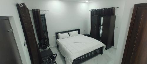 a white bedroom with a bed and a mirror at Kashmir Valley in Kanthalloor
