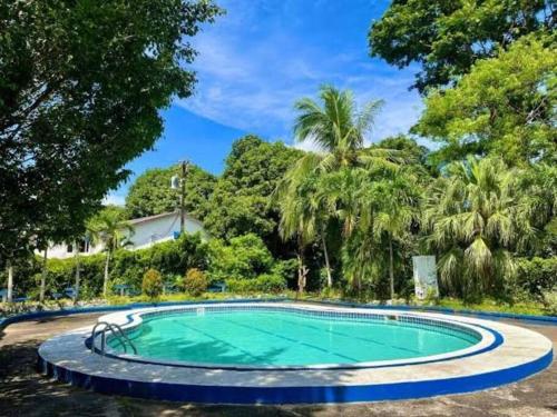 an empty swimming pool with trees and a house at Kiddie Hostel Unit30A-kids and pets friendly in Subic bay freeport zone in Kababae