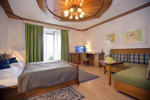 1 dormitorio con cama, sofá y ventana en Seehotel Schwan, en Gmunden