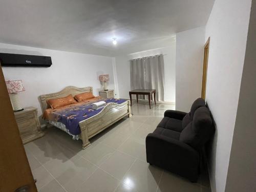 ein Schlafzimmer mit einem Bett, einem Sofa und einem Stuhl in der Unterkunft Casa Carmona in Mendoza