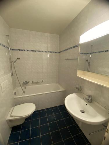 a white bathroom with a toilet and a sink at Chambre a Neuchâtel in Neuchâtel