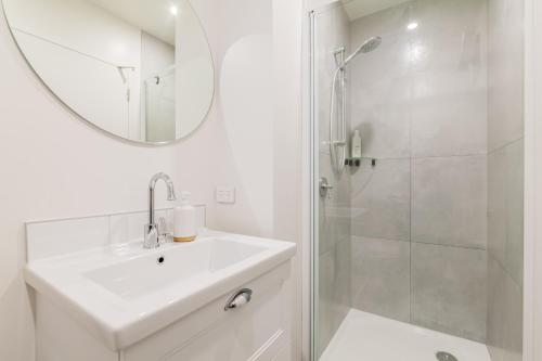 a white bathroom with a sink and a shower at Retro Retreat in Christchurch in Christchurch