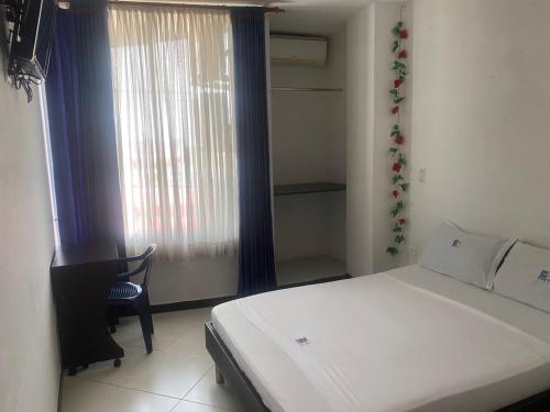 1 dormitorio con cama, ventana y silla en Hotel Milenium en Yopal