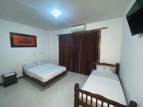 1 dormitorio con 2 camas y ventana en Hotel Milenium en Yopal