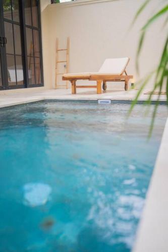 a bench sitting next to a pool with a laptop on it at Villa Benih Uluwatu in Jimbaran