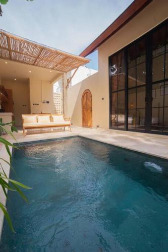 a swimming pool in front of a house at Villa Benih Uluwatu in Jimbaran