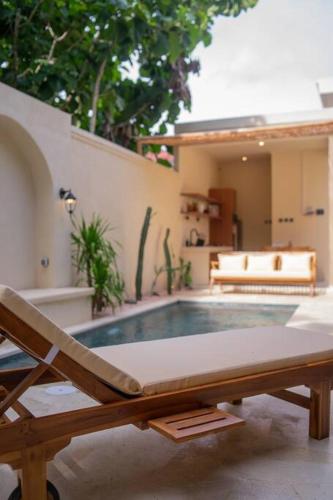 a swimming pool with a chair and a bench at Villa Benih Uluwatu in Jimbaran