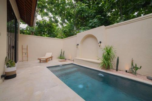 a swimming pool in a patio with a bench and trees at Villa Benih Uluwatu in Jimbaran