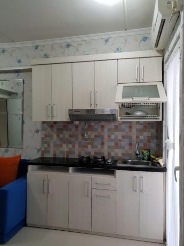 eine Küche mit weißen Schränken und einer Arbeitsplatte in der Unterkunft Apartemen Green Pramuka City Type 2BR Full Furnish in Jakarta