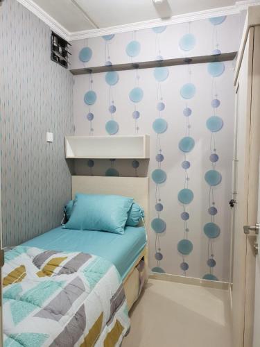 ein Schlafzimmer mit einem Bett und einer Wand mit blauen Kreisen in der Unterkunft Apartemen Green Pramuka City Type 2BR Full Furnish in Jakarta
