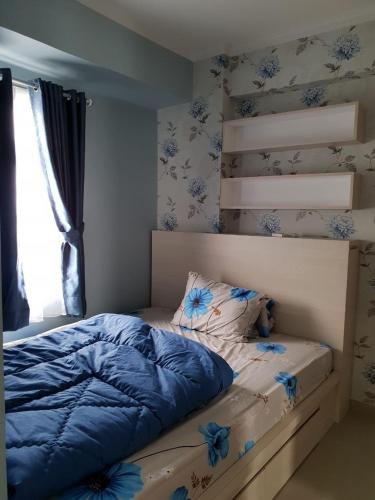 Schlafzimmer mit einem Bett mit blauer Bettwäsche und einem Fenster in der Unterkunft Apartemen Green Pramuka City Type 2BR Full Furnish in Jakarta