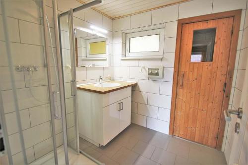 La salle de bains est pourvue d'un lavabo, d'une douche et d'une porte. dans l'établissement Reiher 6, à Mirow