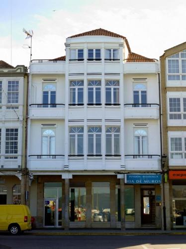 a white building with a balcony on a street at Pension Residencia Ria De Muros in Muros