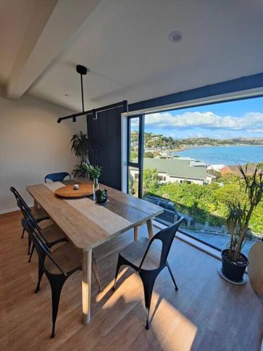 a dining room with a table and chairs and a large window at Sea views in lovely beach side area in Porirua