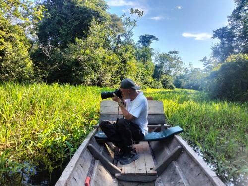 a man sitting on a boat taking a picture with a camera at Amazon Jaguar Adventure & Lodge in Iquitos