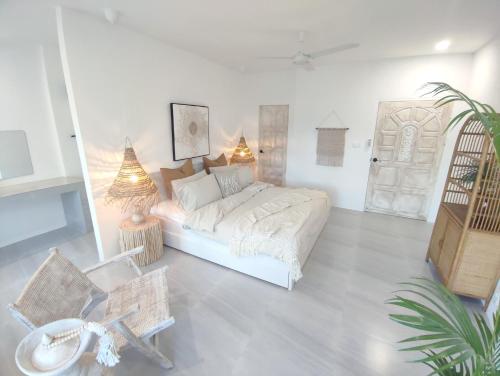 3BR Villa, Bangrak Beach, Koh Samui في كوه ساموي: غرفة نوم بيضاء فيها سرير وطاولة ونبات