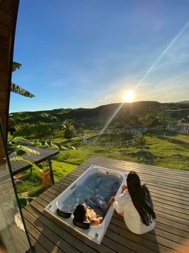 two people in a hot tub on a deck with the sunset at Rancho Navarro in Pôrto de Pedras