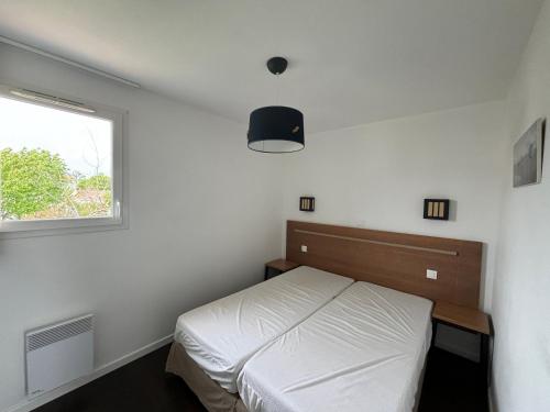 a bedroom with a white bed and a window at Maison 2 chambres au calme avec piscine, proche plages et commerces - FR-1-197-484 in Talmont-Saint-Hilaire
