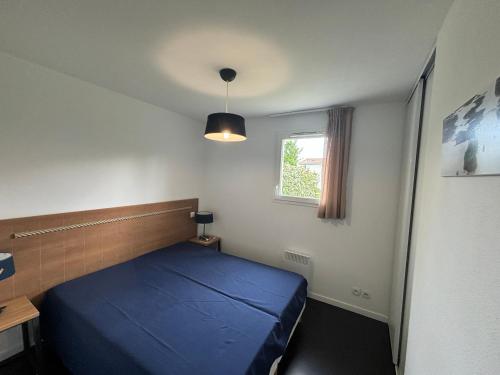 une chambre avec un lit bleu et une fenêtre dans l'établissement Maison de Vacances 2* avec Piscine Chauffée, Proche Plage et Commerces - FR-1-197-492, à Saint-Hilaire-de-Talmont