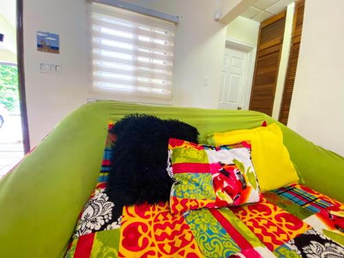 a green bed with colorful pillows and a blanket at Oasis de Tranquilidad in Colón