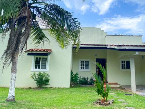 a white house with a palm tree in front of it at Oasis de Tranquilidad in Colón