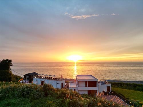 a sunset over the ocean with a white house at private villa クニウミ之チ in Awaji