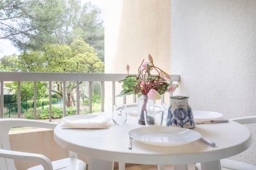 une table blanche avec des assiettes et un vase avec des fleurs dans l'établissement Appartement Samoa - Welkeys, à Saint-Mandrier-sur-Mer