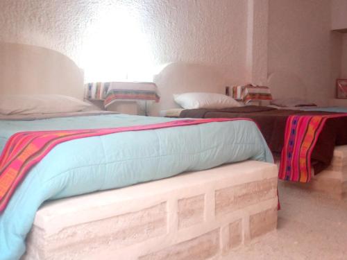 a room with two beds and a bench in it at Hostal Beds of salt Ga in Uyuni