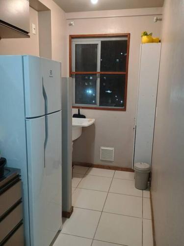 cocina con nevera, fregadero y ventana en Apartamento no bairro João Pessoa, en Jaraguá do Sul
