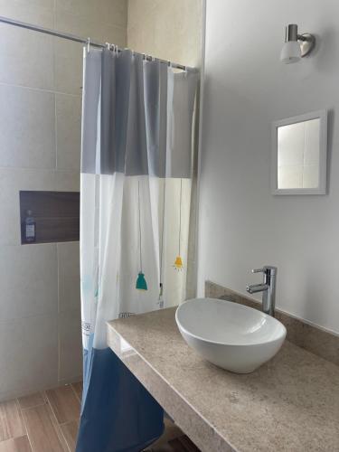 a bathroom with a sink and a shower curtain at Departamento Bohen 13 in Mérida
